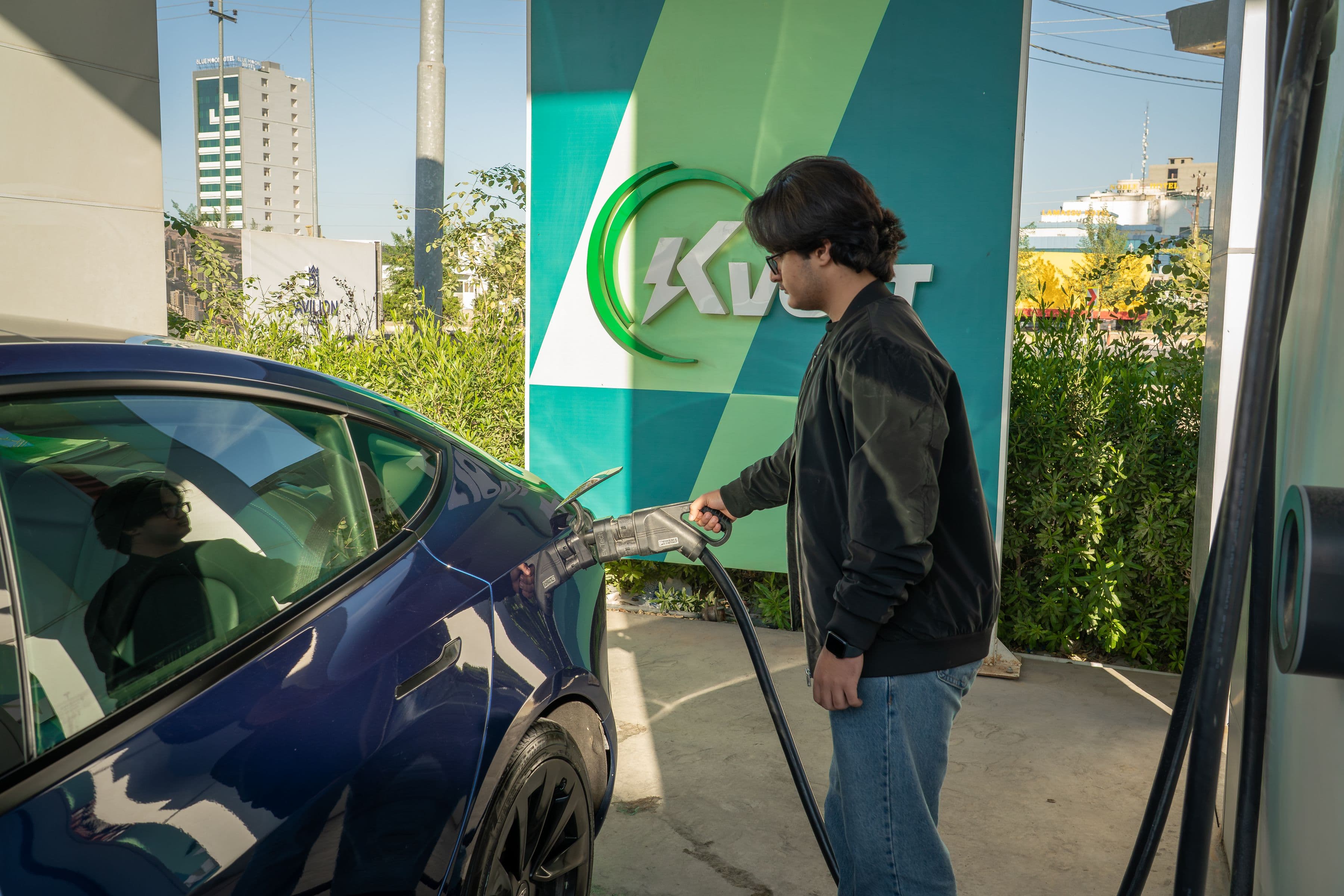 Condutor a carregar um veículo elétrico num posto de carregamento ao ar livre